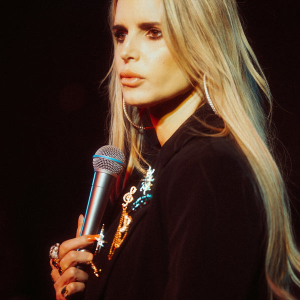 Jessica Simpson holding a microphone against a dark background