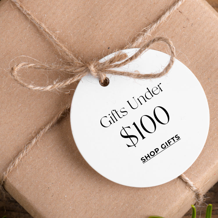 Gift wrapped in brown paper with a white tag reading Gifts Under $100 Shop Gifts. Shop gifts under $100.