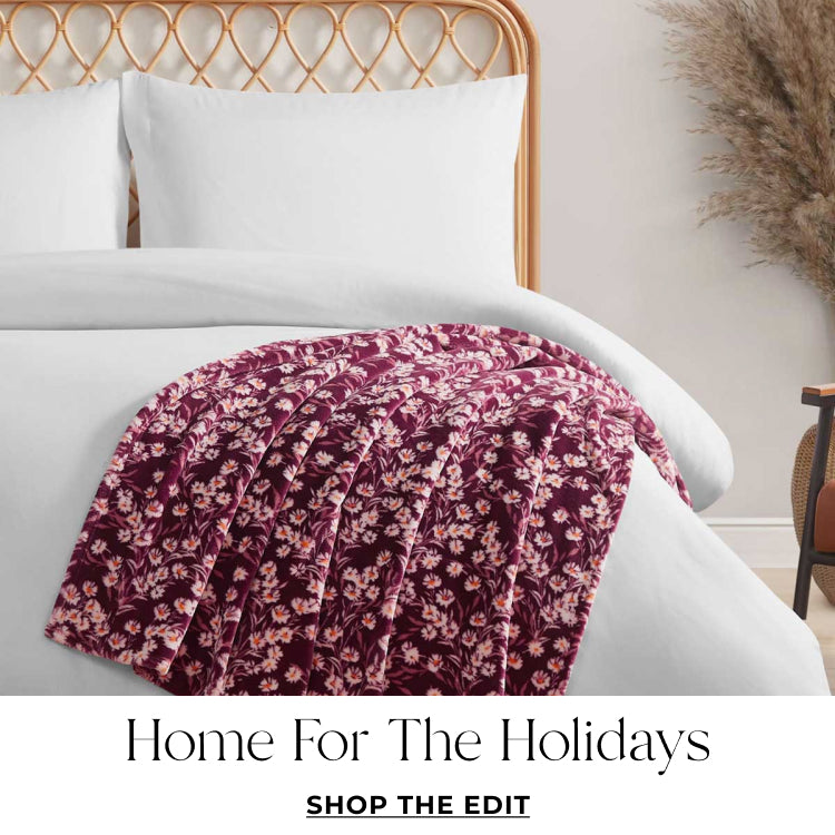 Floral-patterned blanket on a bed with 'Home for the Holidays' text.Shop the edit. 