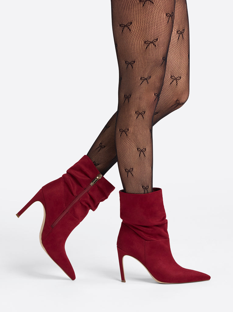 Red high-heeled boots worn with black tights featuring bow patterns on a white background