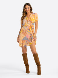 Woman wearing a colorful patterned dress with brown knee-high boots on a white background