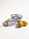Two pairs of sunglasses on white blocks with lemons on a white background